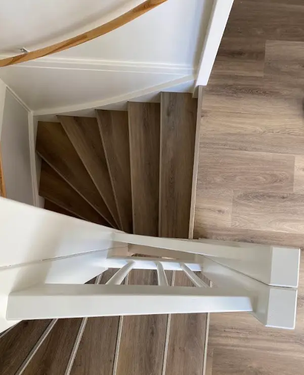 Traprenovatie met donkere treden Zwevende trap met donkere PVC treden boven een lichte visgraatvloer