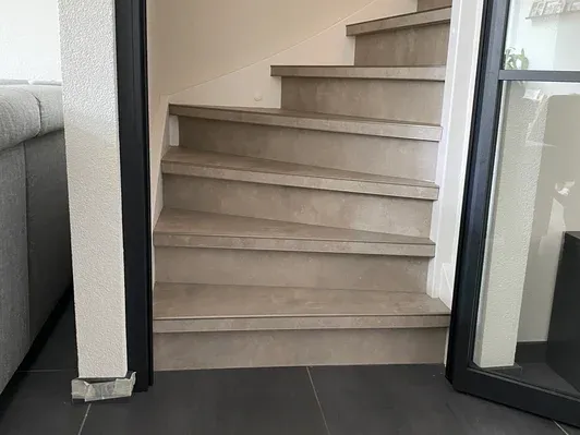 Dichte trap in warm grijs Dichte trap gerenoveerd met grijze PVC treden en afwerkstrippen