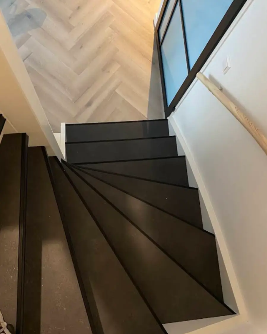 PVC traprenovatie Gerenoveerde zwevende trap met donkere PVC treden die aansluit op een lichte visgraatvloer